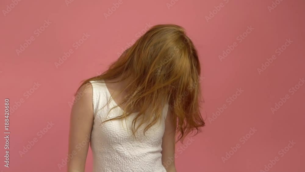 Beautiful teenage girl with red blowing hair and blue eyes on pink background Beautiful teenage girl with red blowing hair and blue eyes on pink background