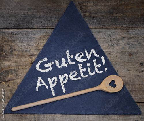 Schriftzug aus Kreide Guten Appetit auf Tafel und Holzlöffel mit Herz