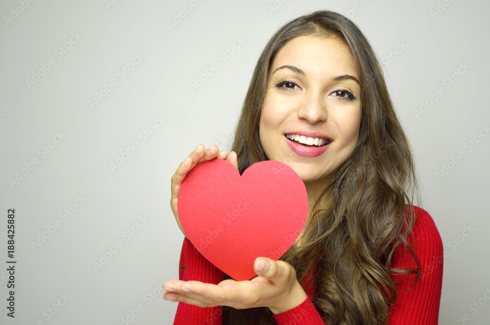 Portrait of a sweet perfect girl smiling at camera with heart shaped paper in her hands. Valentine's Day concept. Portrait of a sweet perfect girl smiling at camera with heart shaped paper in her hands. Valentine's Day concept.