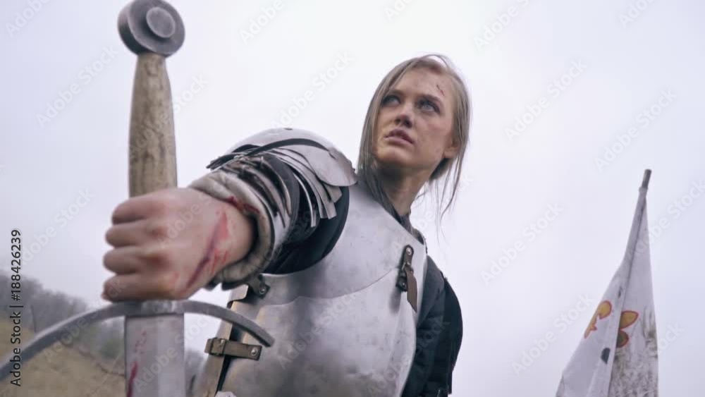 Masculine Jeanne Dark all in wounds is looking into the distance and holding a sword Masculine Jeanne Dark all in wounds is looking into the distance and holding a sword