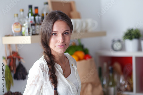 Young woman standing near desk in the kitchen. Young woman .