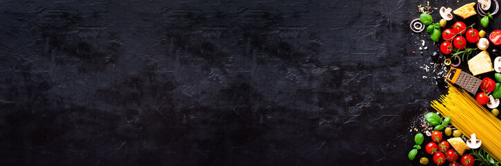Food ingredients for italian pasta, spaghetti on black stone slate background. Copy space of your text. Banner