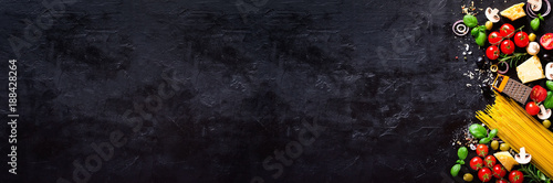 Food ingredients for italian pasta, spaghetti on black stone slate background. Copy space of your text. Banner photo
