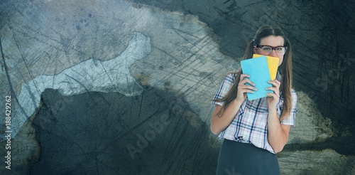 Composite image of geeky hipster hiding her face behind notepad 