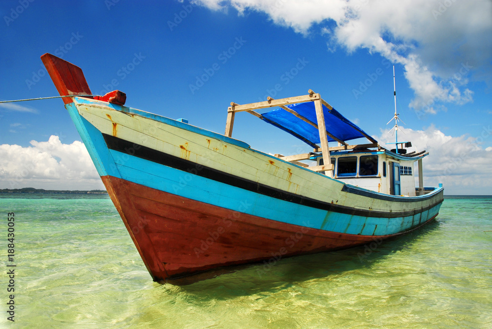 A colorful wooden boat moored on a beach at Belitung Island, Indonesia. 