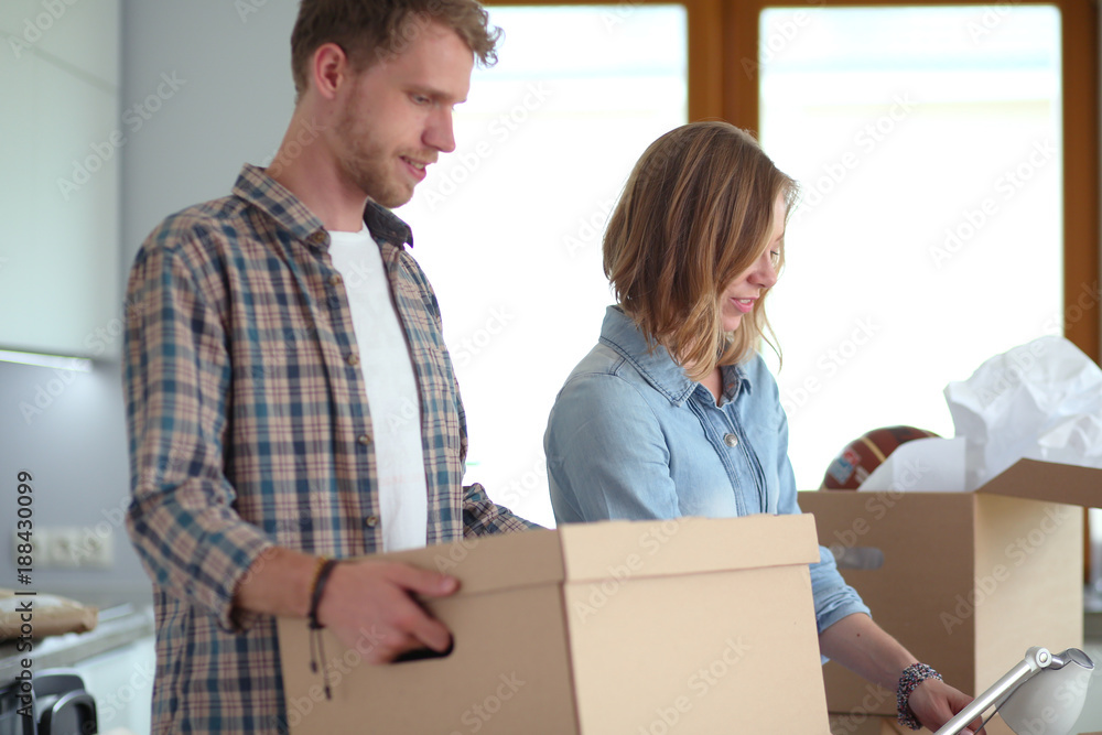 Couple unpacking cardboard boxes in their new home. Young couple. Couple unpacking cardboard boxes in their new home. Young couple.