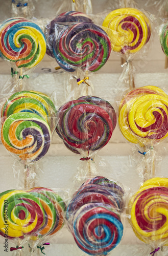 Colorful rainbow-swirl lollipops on display on the shelves in the market,