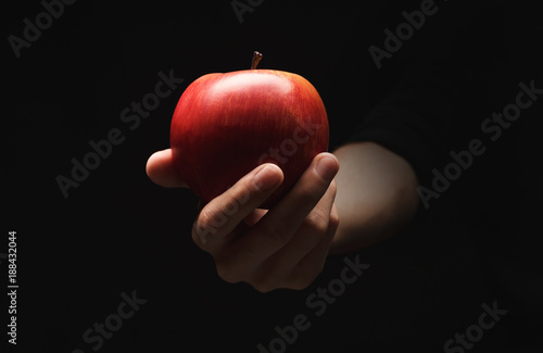 Red ripe apple on male hand, isolated on black
