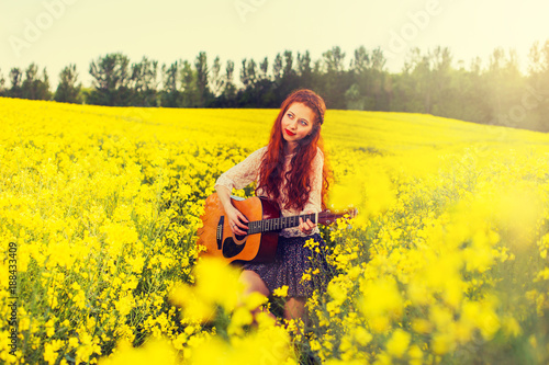 Young ginger hair girl in 70s style with acoustic guitar