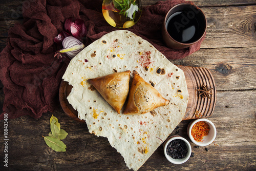 Asian Uzbek samsa dish with meat on pita bread with a glass of wine with spices on a wooden table