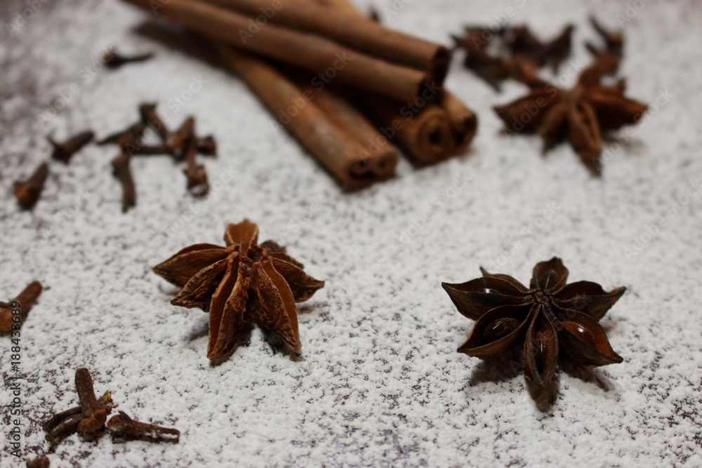 Cinnamon sticks and anise stars closeup on powdered sugar table. Cooking and baking background. Aromatic condiment and spices. Healthy food ingredients. Cooking decoration. Desserts ingredients. Cinnamon sticks and anise stars closeup on powdered sugar table. Cooking and baking background. Aromatic condiment and spices. Healthy food ingredients. Cooking decoration. Desserts ingredients.