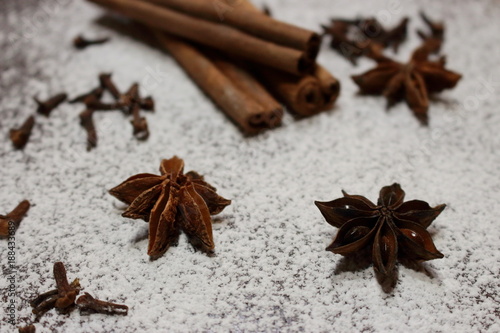 Cinnamon sticks and anise stars closeup on powdered sugar table. Cooking and baking background. Aromatic condiment and spices. Healthy food ingredients. Cooking decoration. Desserts ingredients.