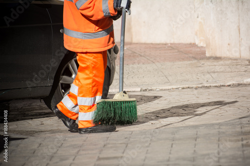 Horizontal View of a Dustman Cleaning the Street With a Mop Wearing an Orange Uniform