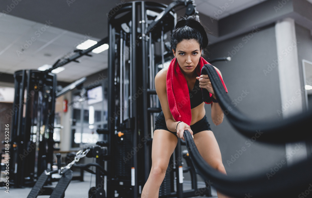 Cross-fit workout motivation. People, sport concept. Athletic sportive young fit female working out in functional training gym doing crossfit exercise with battle ropes, copyspace for your text. Cross-fit workout motivation. People, sport concept. Athletic sportive young fit female working out in functional training gym doing crossfit exercise with battle ropes, copyspace for your text.