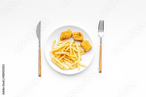 Fast food reastaurant. Chiken nuggets and french fries on plate on white background top view