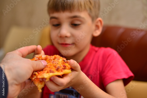 boy in red T-shirt eating pizza at home. portrait of a young man eating pizza  background