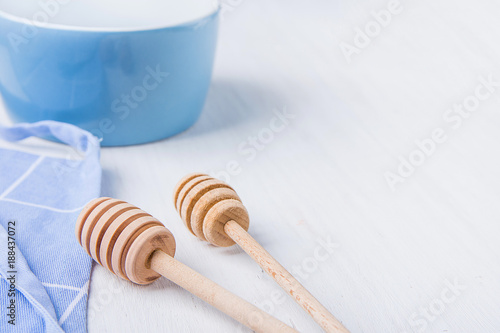 Blue Empty Bowl Wooden Honey Dippers Spoons Cotton Apron on White Table. Holiday Baking Cooking Concept. Christmas Easter. Kitchen Interior. Social Media Blog Recipe Template © olindana