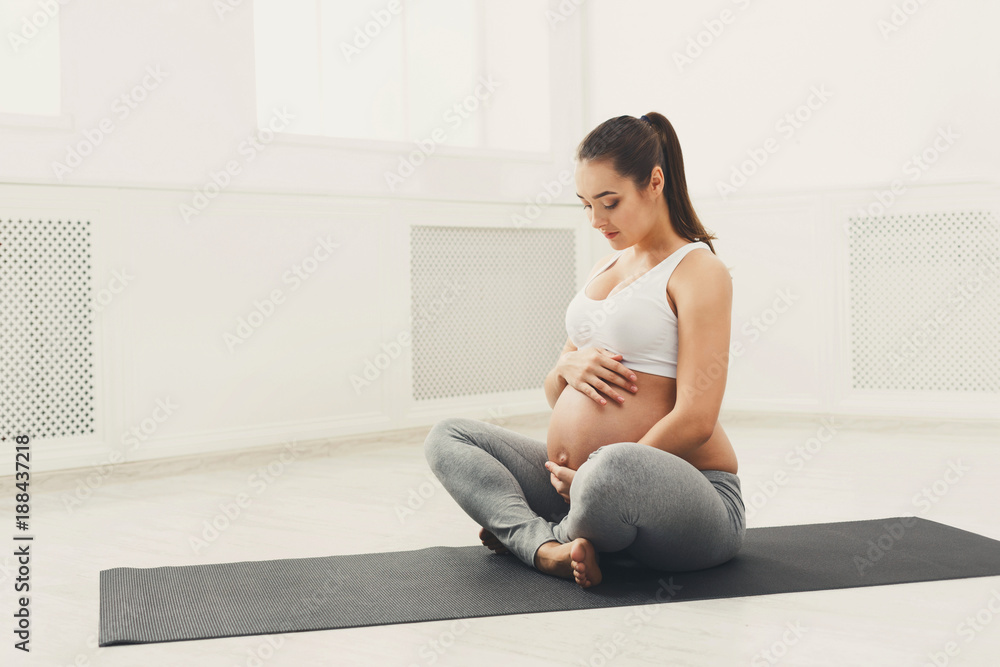 Pregnant woman caressing her belly at home