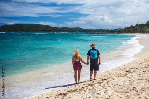 loving couple of travelers holding hands walk on a Caribbean beach