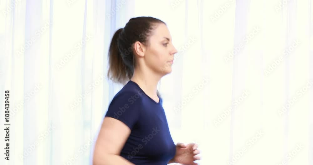 Attractive girl running on the treadmill in the small sport gym or home. Attractive girl running on the treadmill in the small sport gym or home.