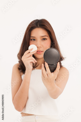 An attractive Asian girl with cosmetic powder smiling on white background.