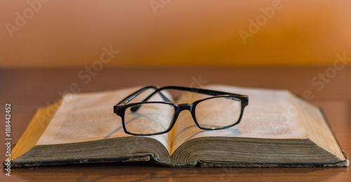 Open old book with retro glasses on top of it close up