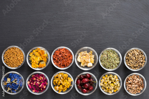 Selection of dried herbs on a dark background with copy space, top view