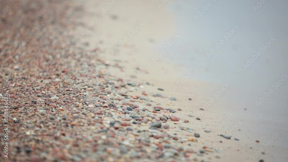 Wave washed stones on sand beach. Close up