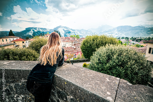 Fotografie Young woman overlooking the terrace of Barga, Lucca, Tuscany, admires the mounta