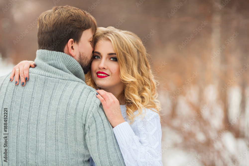 beautiful young couple in love in sweaters walking on snowy forest park beautiful young couple in love in sweaters walking on snowy forest park