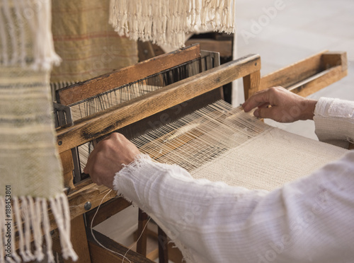 Hands of a man weaving on a loom photo