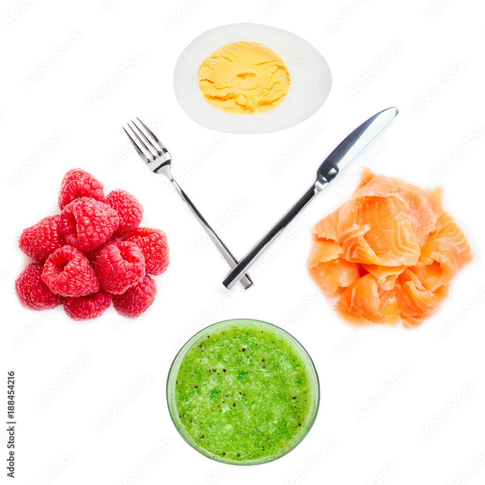 Concept of a diet. Eating during the day: Boiled egg and raspberry, fish and smoothies on clock with a fork and knife. Concept of a diet. Eating during the day: Boiled egg and raspberry, fish and smoothies on clock with a fork and knife.