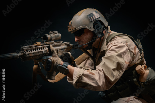 special forces soldier of the united states poses with a rifle on a black background