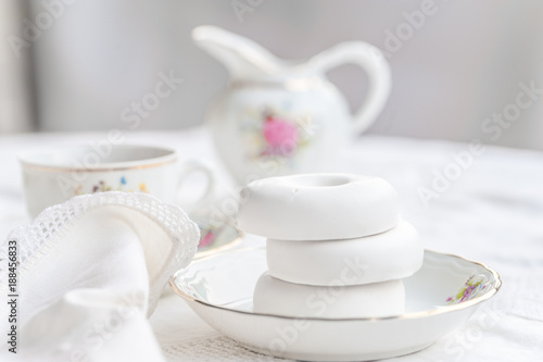 Luxury porcelain tea set on white tablecloth with white bagels on a plate