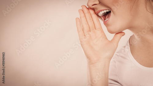 Woman talking gossip with hand close to lips photo