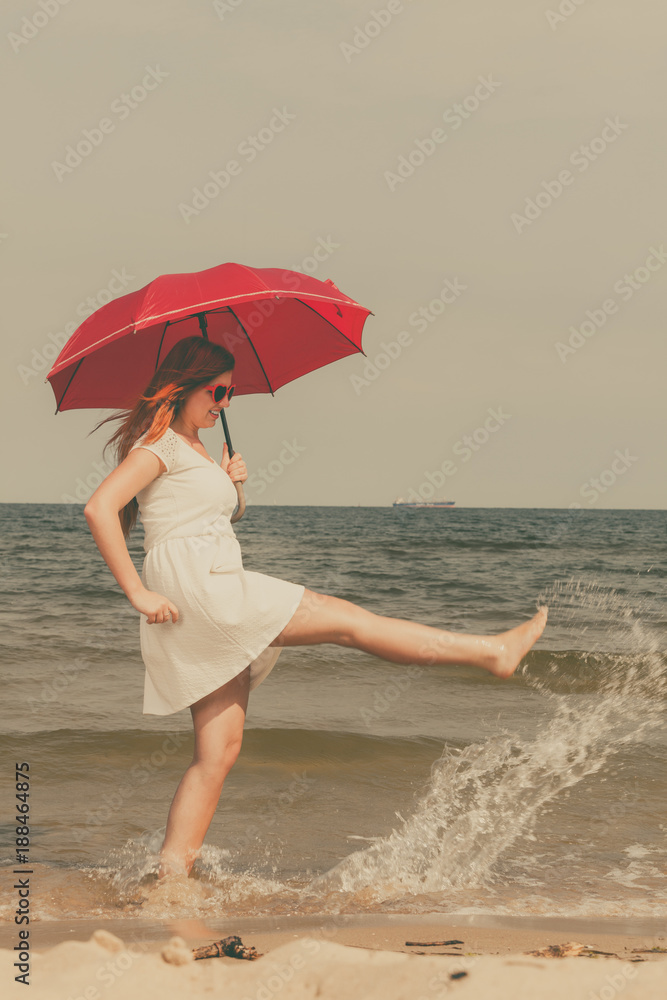 Redhead woman walking on beach holding umbrella Redhead woman walking on beach holding umbrella