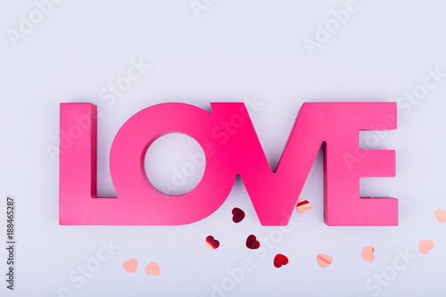 Red sign LOVE and glitter heart confetti. Valentine day concept. Trendy minimalistic flat lay design background