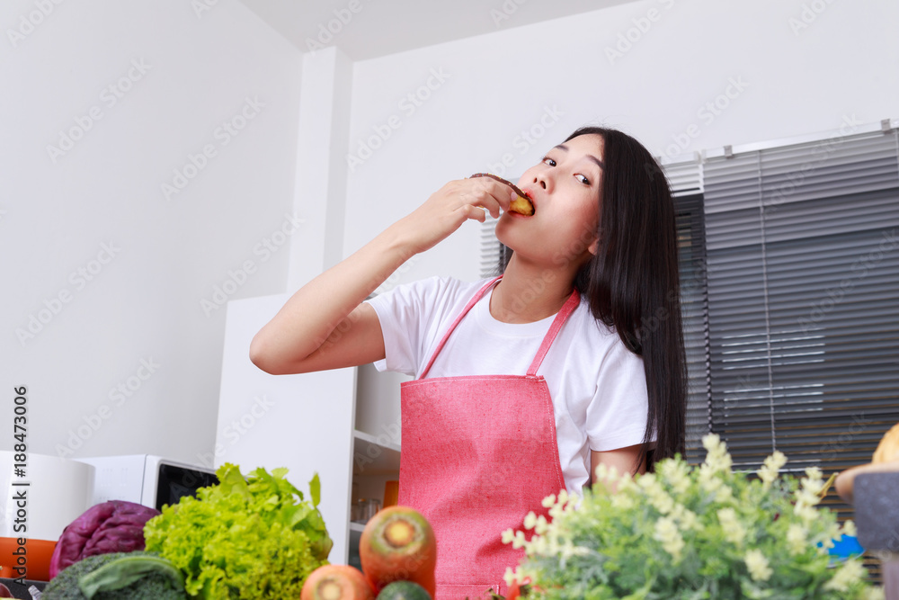 woman eating a chocolate donut in kitchen room woman eating a chocolate donut in kitchen room