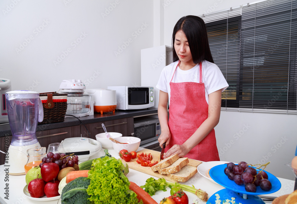 woman cutting tomato on board in kitchen room