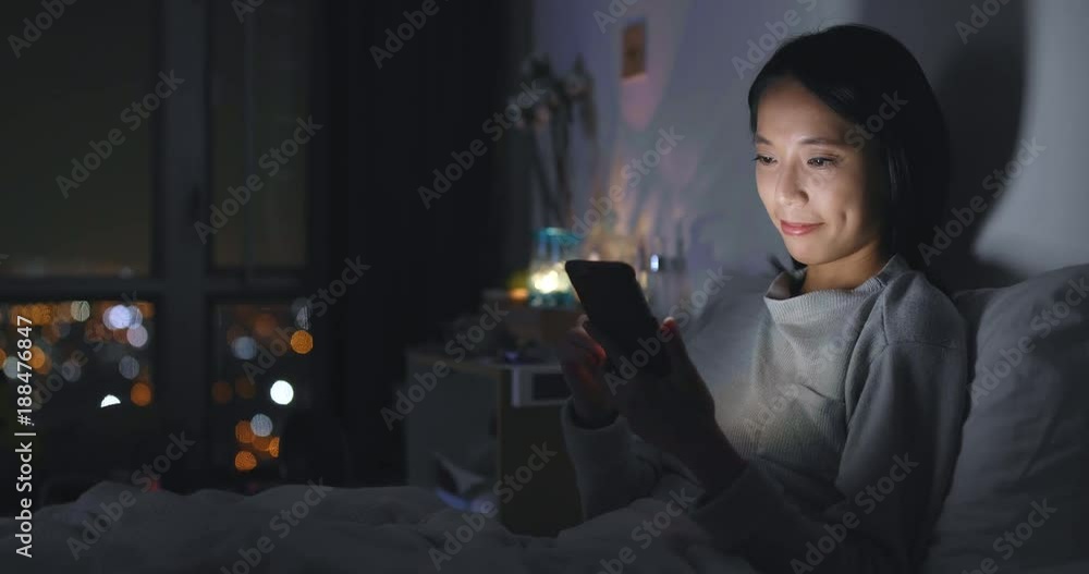 Woman use of cellphone at bedroom in the evening Woman use of cellphone at bedroom in the evening