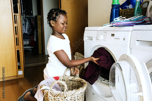 Young teen girl washing clothes using washing machine