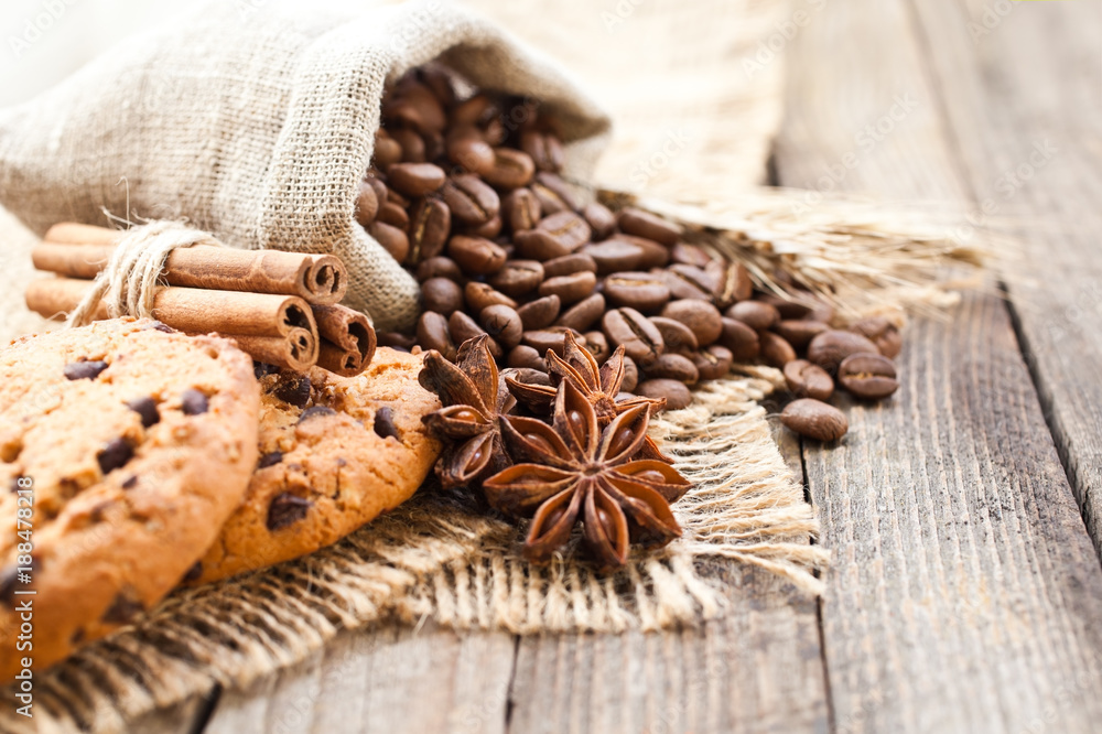 Fototapeta premium Coffee beans with biscuits and spices on canvas fabric closeup