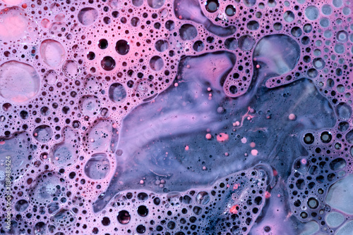 Toxic chemical acrylic oil droplets on water foam creating the idea of pollution concepts ideas and themes in bright vibrant colours, as the circle globules release on the liquid surface. 