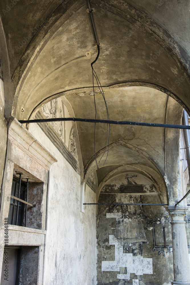 A naked cable on the ceiling of a building with arches in a decaying style.