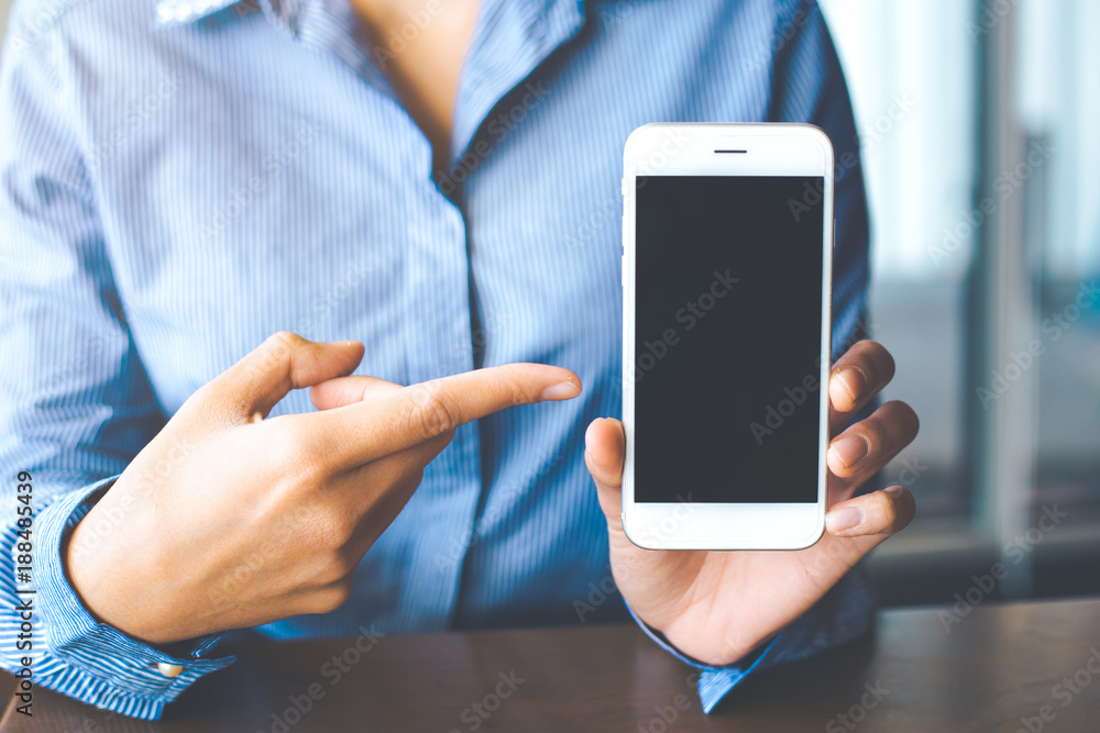Women hand show the white mobile phone at the blank screen in the office.
