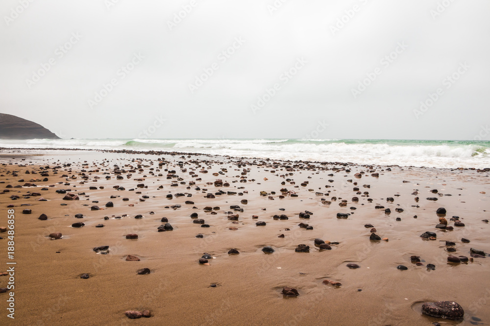 Coast, waves and beach with yellow sand and pebbles