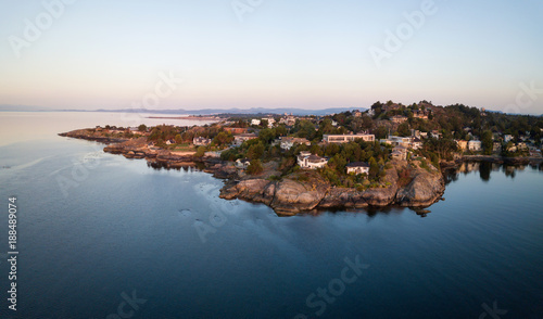 Fototapeta Naklejka Na Ścianę i Meble -  Aerial panorama of beautiful and luxury homes on the rocky coast during a vibrant sunrise. Taken in Victoria, Vancouver Island, BC, Canada.