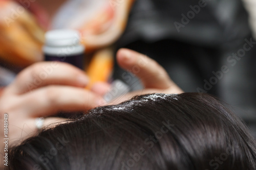 Female hand puts powder for volume on dark hair, close-up.