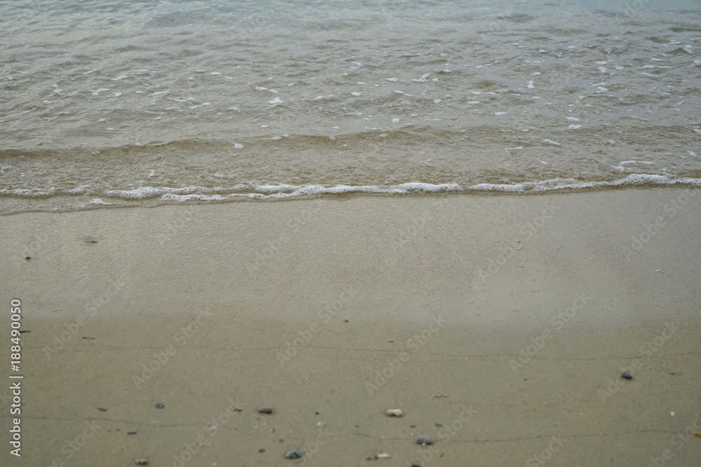 Soft sand and small rock beach with sea water and white foamy wave background and copyspace on Ornos shore Soft sand and small rock beach with sea water and white foamy wave background and copyspace on Ornos shore