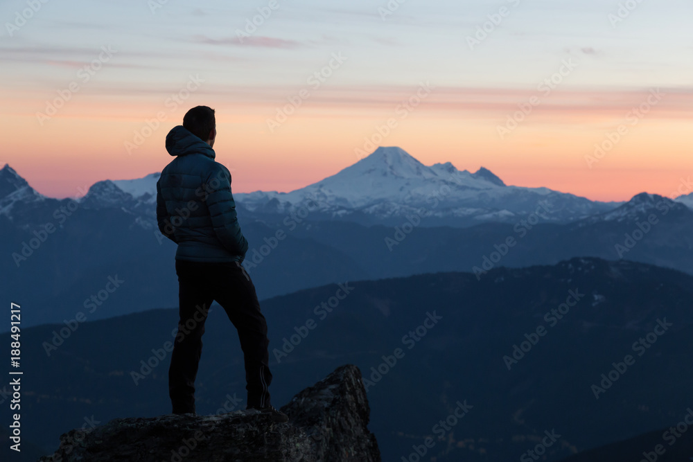 Fototapeta premium Adventurous man on top of the mountain during a vibrant sunset. Taken on Cheam Peak, near Chilliwack, East of Vancouver, British Columbia, Canada.